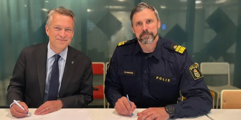 Stadsdirektör och polisman sitter vid ett bord och skriver under samverkansavtal.