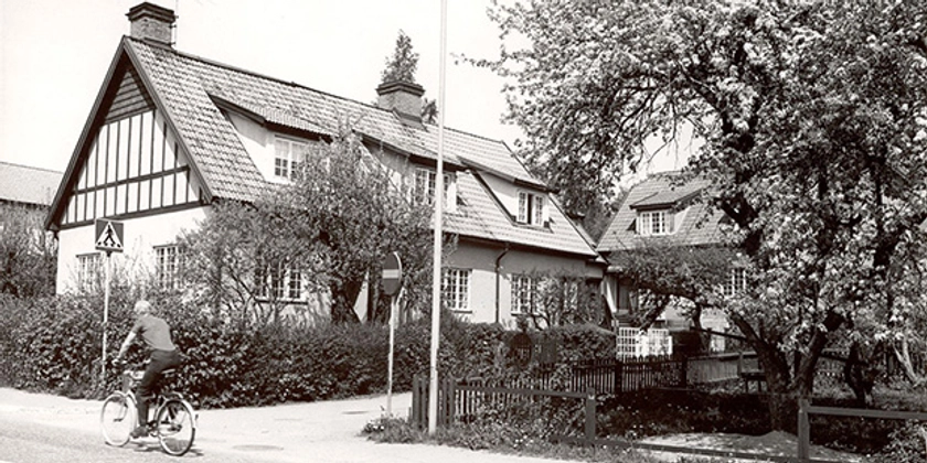 Ett svartvitt foto av en cyklist i ett bostadskvarter.
