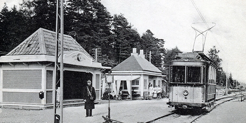 Ett svartvitt foto av ett tåg som står på en station. 