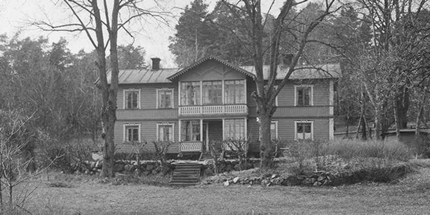 Ett svartvitt foto av en villa med utsirade trädetaljer och punschveranda.