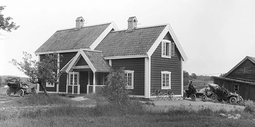 Ett svartvitt foto av en äldre gård med dåtidens bilar.