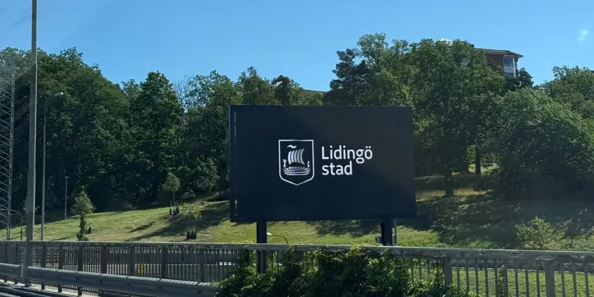 En stor digital skylt vid sidan av vägen där det står Lidingö stad