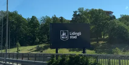 En stor digital skylt vid sidan av vägen där det står Lidingö stad