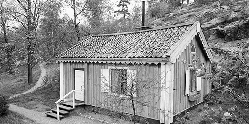 Ett svartvitt foto av en liten stuga.
