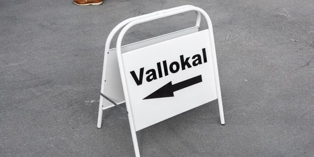 En vit skylt med texten vallokal och en pil som pekar åt vänster.