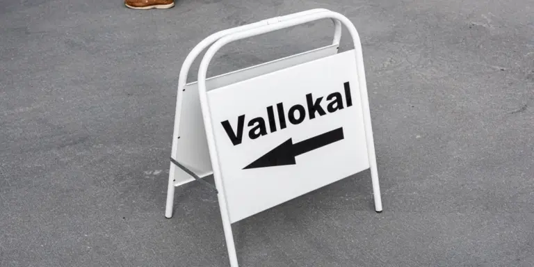 En vit skylt med texten vallokal och en pil som pekar åt vänster.