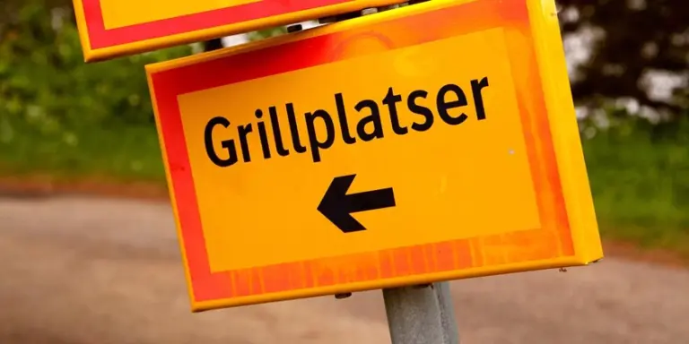 En gul vägskylt med en pil som pekar åt höger för hänvisning till grillplatser.