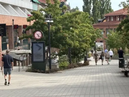 Torget i Lidingö centrum med utslagna gröna träd och människor i rörelse