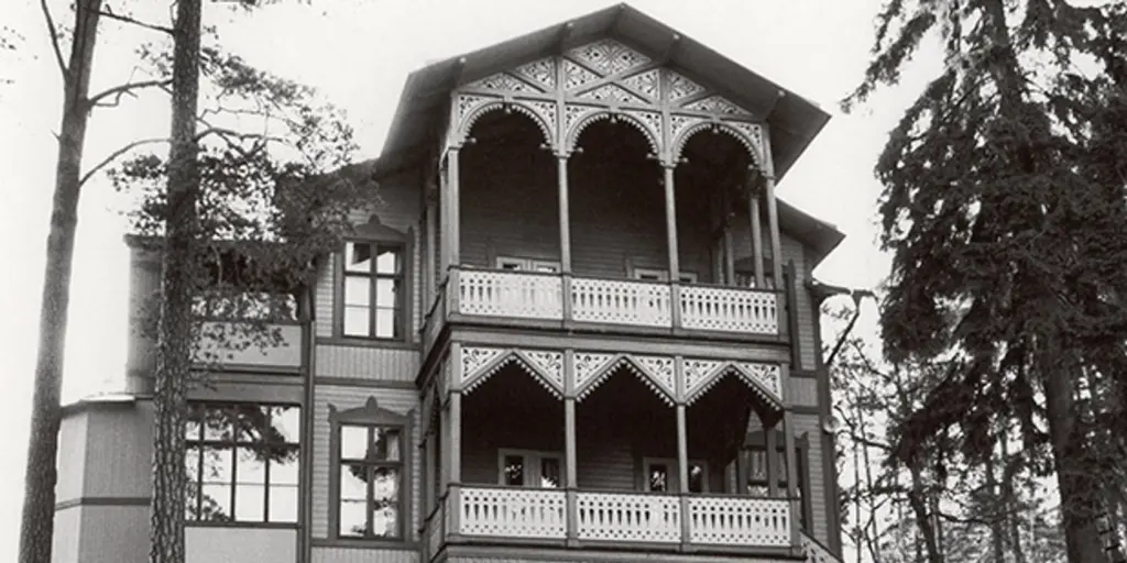 Ett svartvitt foto av en villa i schweizerstil med dekorerad dubbelveranda.