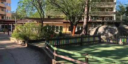 En park med ett staket och en byggnad i bakgrunden.