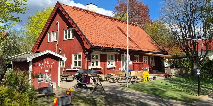 Röd tvåvånings villa i en lummig trädgård.