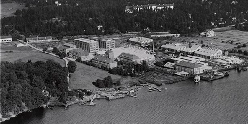 Ett svartvitt flygfoto av ett industriområde vid vattnet.