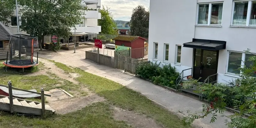 Bakgård med en lekplats och gräsmatta.