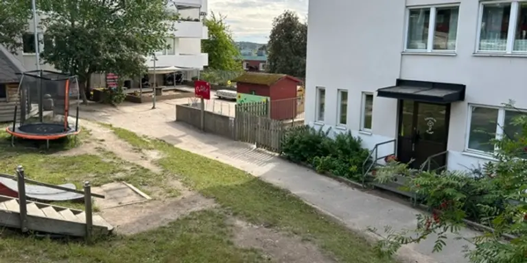 Bakgård med en lekplats och gräsmatta.