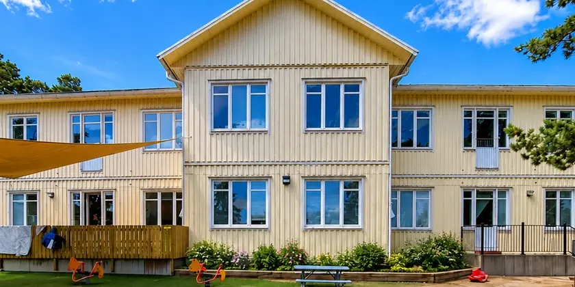 Ett stort ljust hus med leksaker framför.
