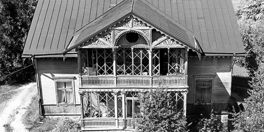 Ett svartvitt foto av ett hus i schweizerstil med dubbla verandor.