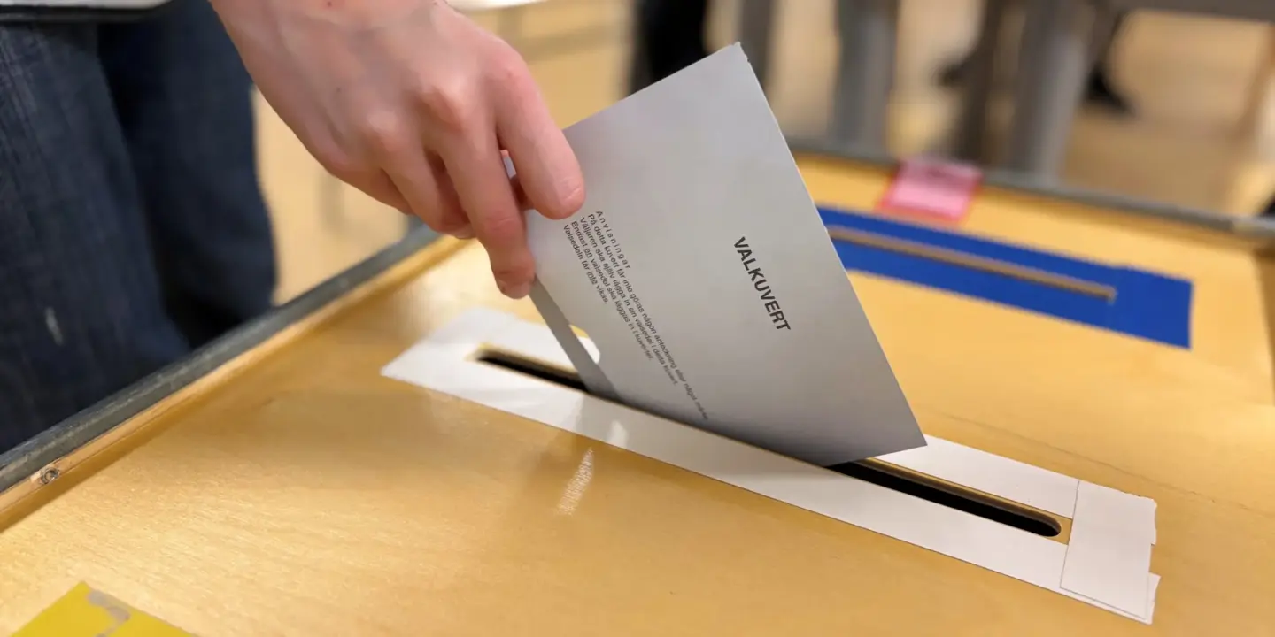 En röstmottagare lägger ett valkuvert i facket för kommunal valet. 