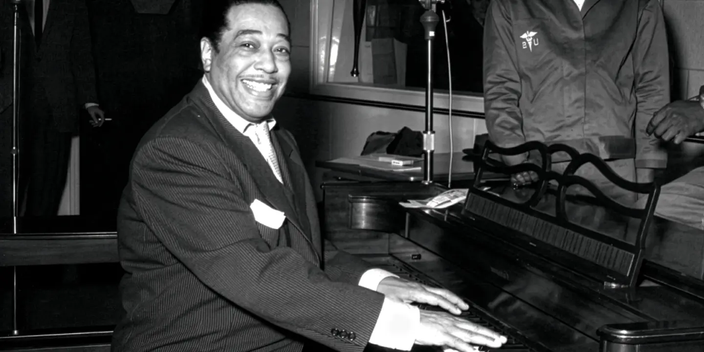 Duke Ellington sitter vid ett piano.