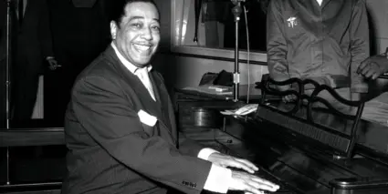 Duke Ellington sitter vid ett piano.