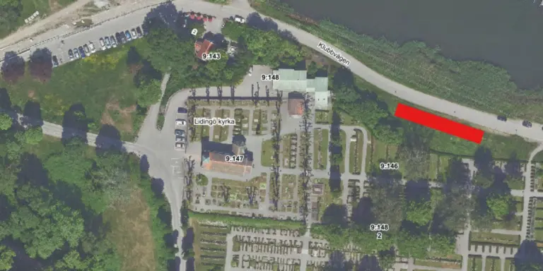 En flygbild över Kyrkviken som inkluderar Lidingö kyrka, skog och parkeringsplatser samt en röd markering längs Klubbvägen.