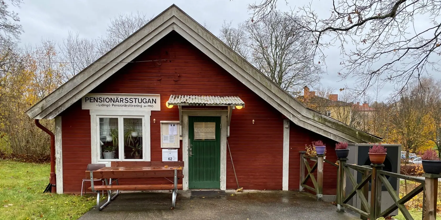 En liten röd byggnad med en grön dörr.