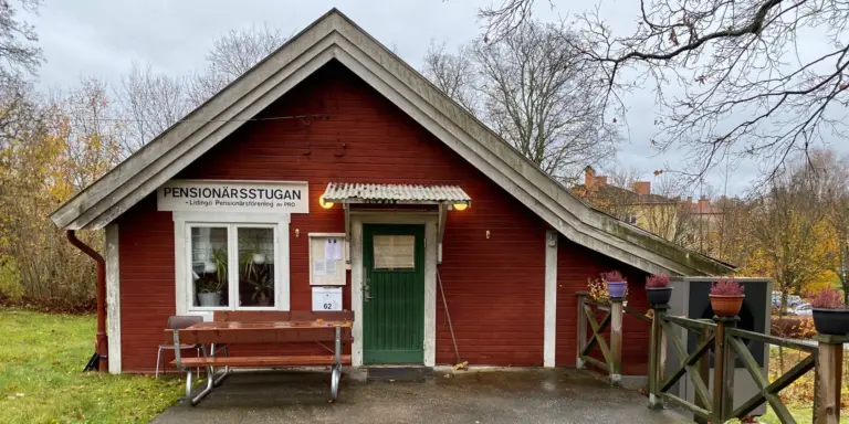 En liten röd byggnad med en grön dörr.